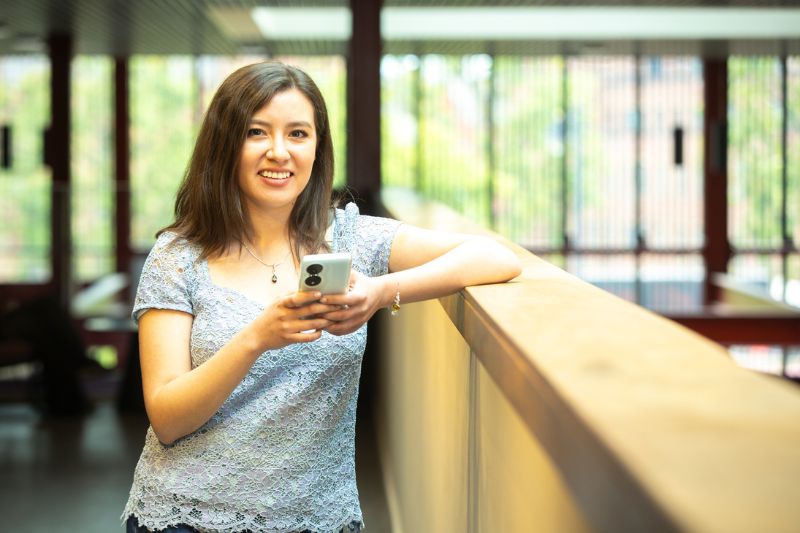 student standing looking at mobile phone